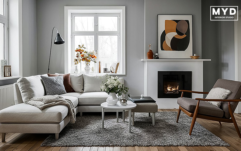 Modern Scandinavian living room with grey walls, a white sectional sofa, fireplace, and abstract wall art